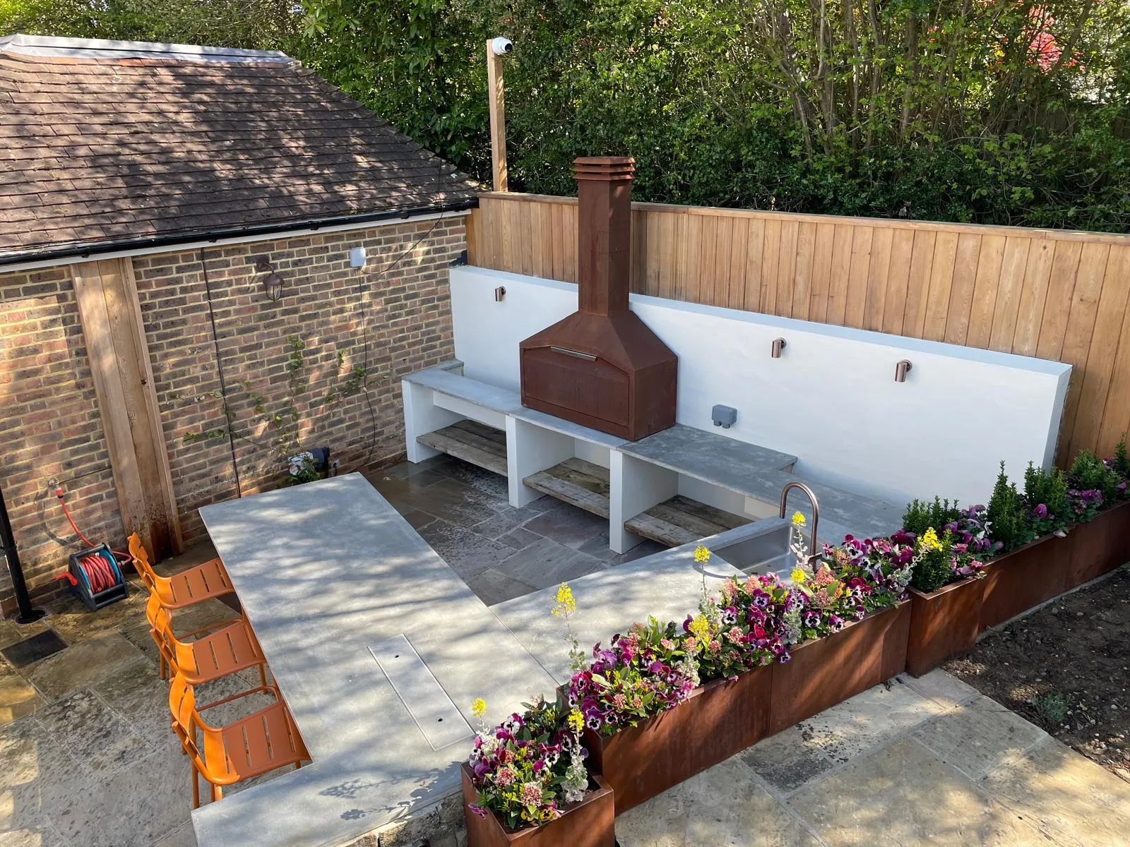 A backyard with a wood stove and flower beds.