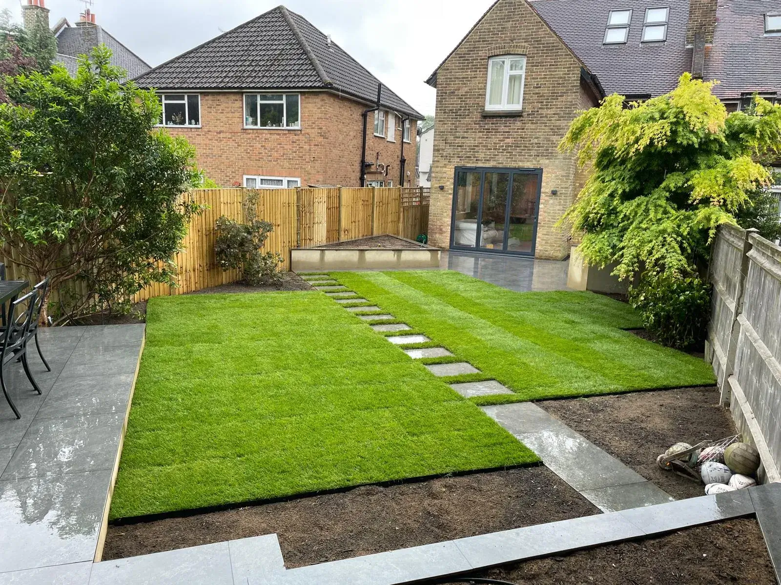 A backyard with a lawn and steps leading to the back of the house.