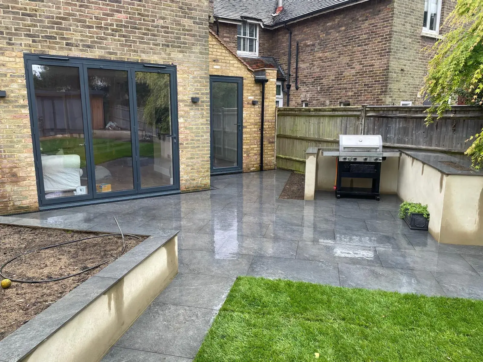 A back yard with a grill and a patio.