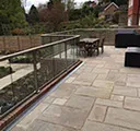 patio with a glass barrier leading to a garden